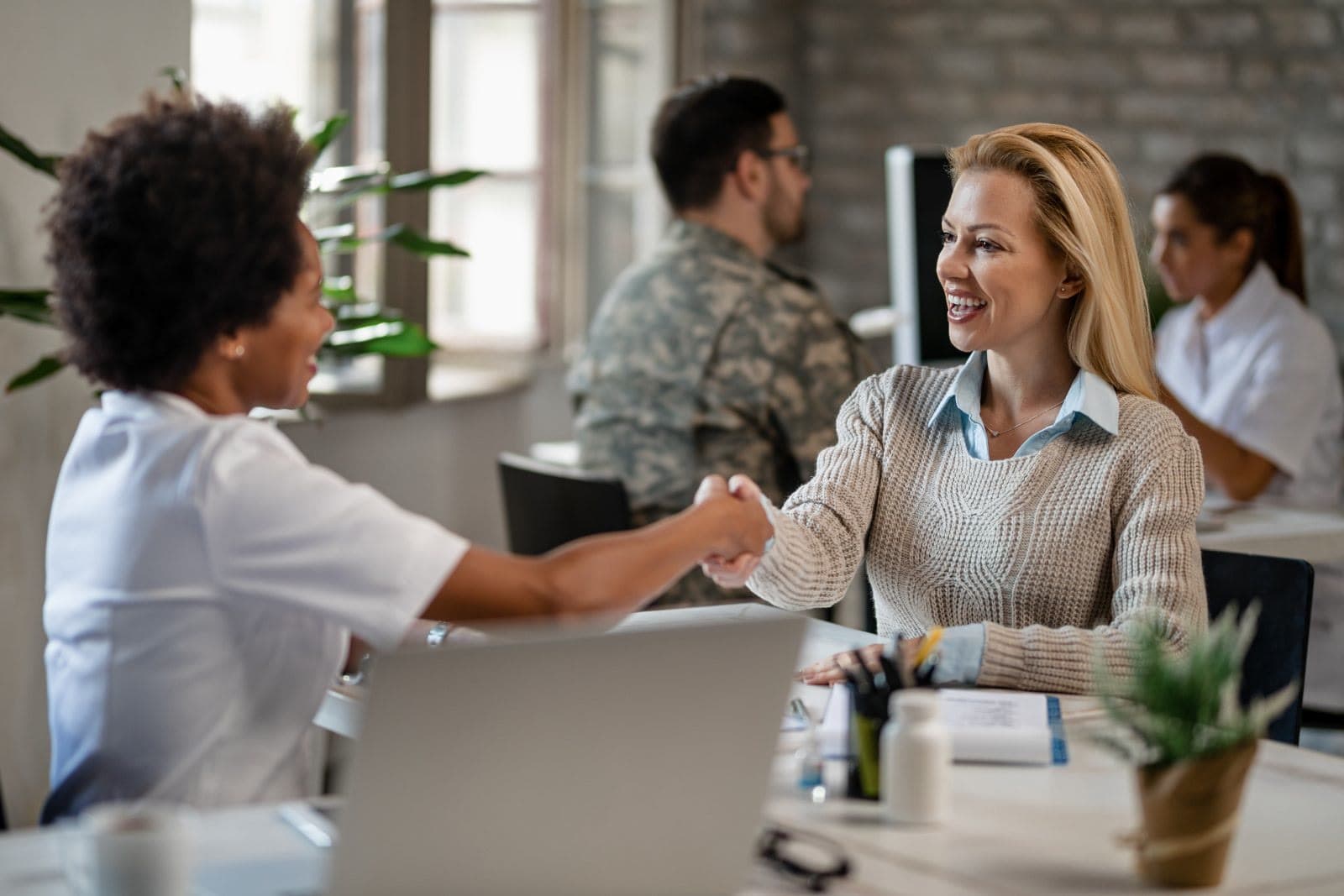 A new hire shaking hands and being welcomed at a desk in an office